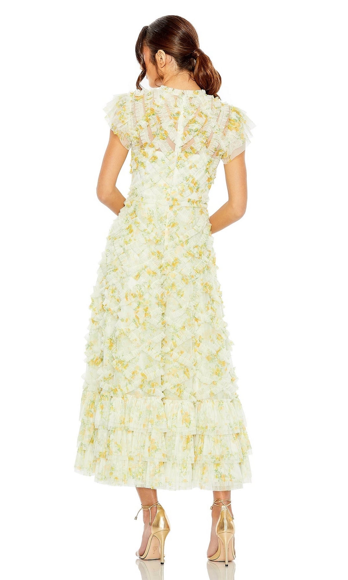 Woman in the Mac Duggal Knee Length Wedding Guest Dress 8009, light yellow with floral print, ruffled tiers and short sleeves, stands with her back to the camera in gold heels—a chic choice for any wedding guest.